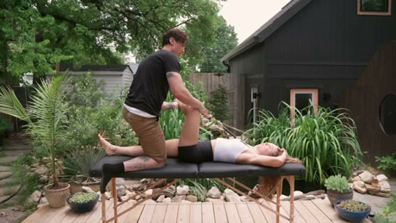 Matthew Jenkins guiding a client through an assisted stretch on a portable table.